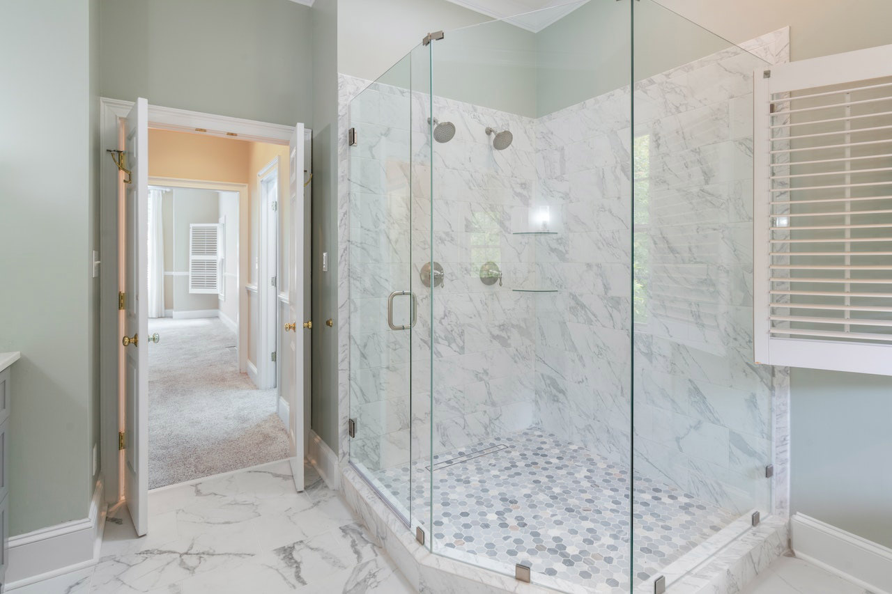A bathroom with a glass shower stall and marble floors.